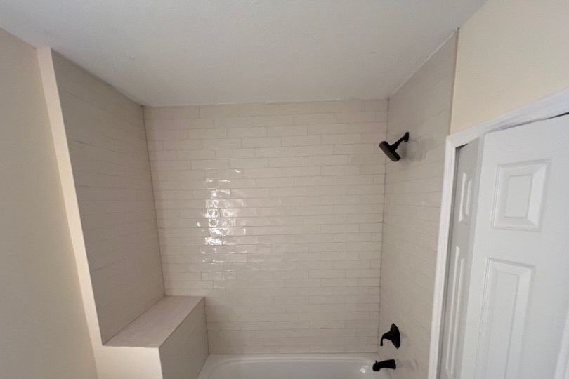 Same bathroom after remodel with white subway tile and matte black fixtures