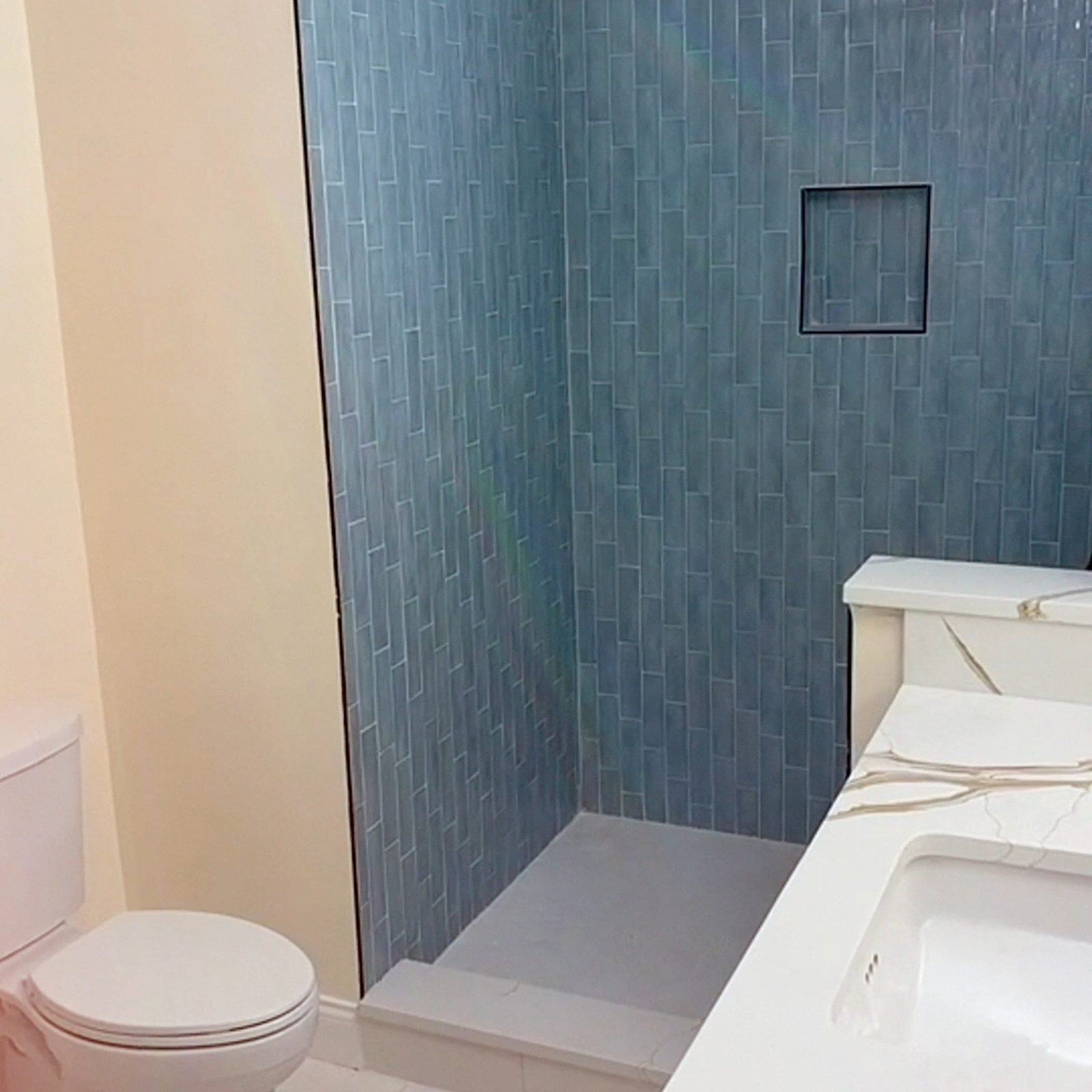 Primary bathroom transformation with vertical blue tile walk-in shower