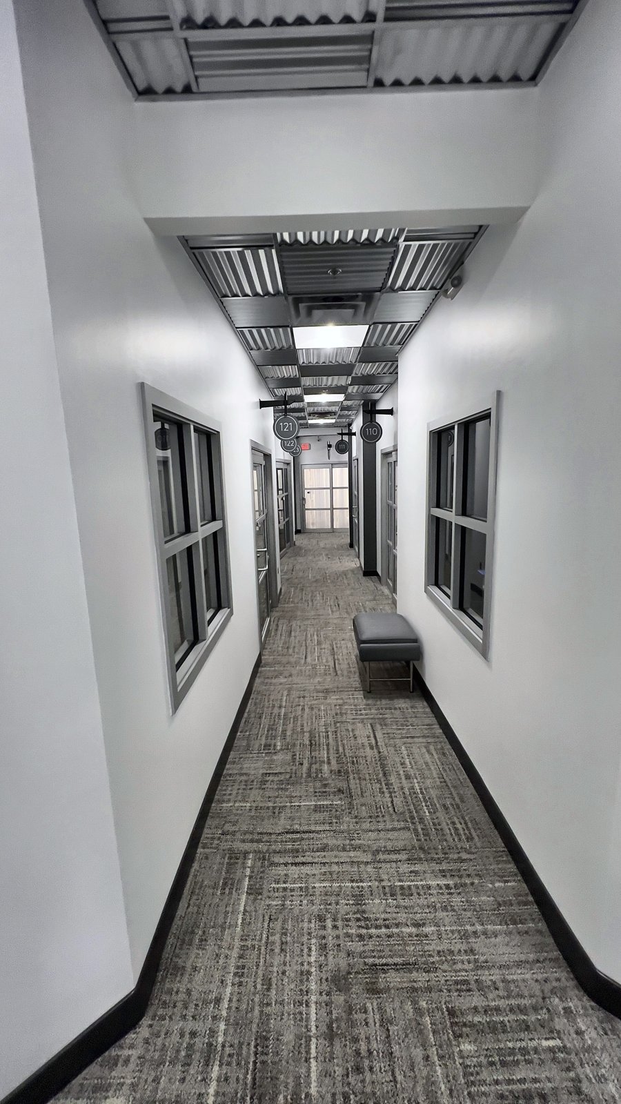 Second hallway view at Sola Salons showing herringbone carpet tile, new wall base and paint — commercial renovation Altamonte Springs